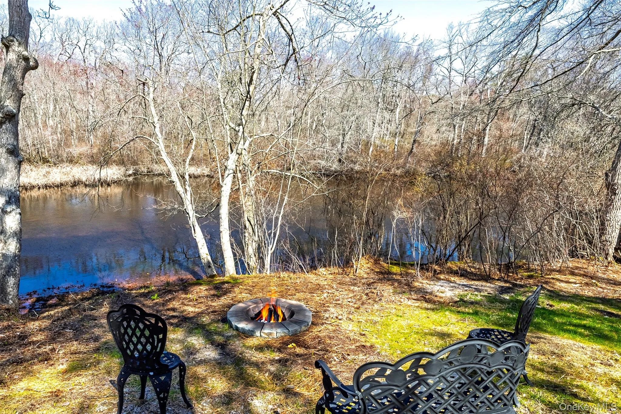 View of yard featuring an outdoor fire pit and a water view View of yard featuring an outdoor fire pit and a water view