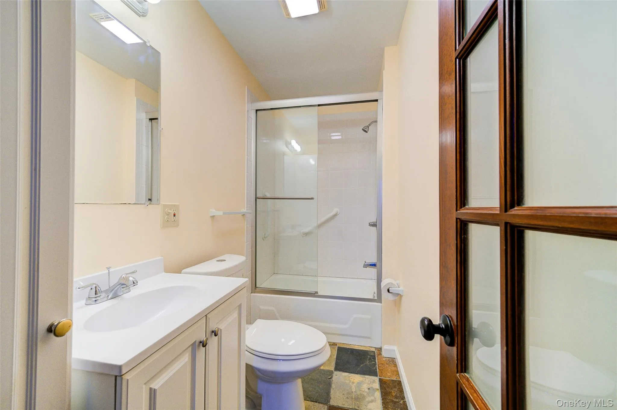 Full bathroom featuring shower / bath combination with glass door, vanity, and toilet Full bathroom featuring shower / bath combination with glass door, vanity, and toilet