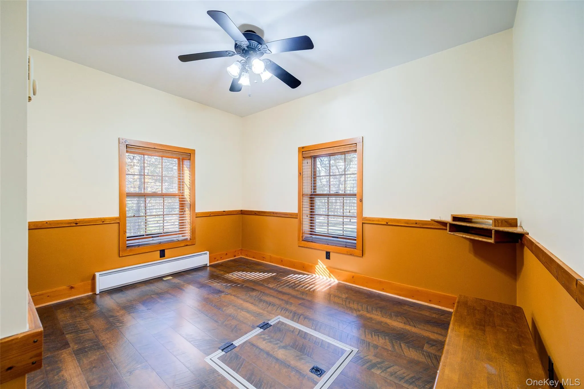 Spare room featuring dark hardwood / wood-style floors, ceiling fan, and a baseboard heating unit Spare room featuring dark hardwood / wood-style floors, ceiling fan, and a baseboard heating unit