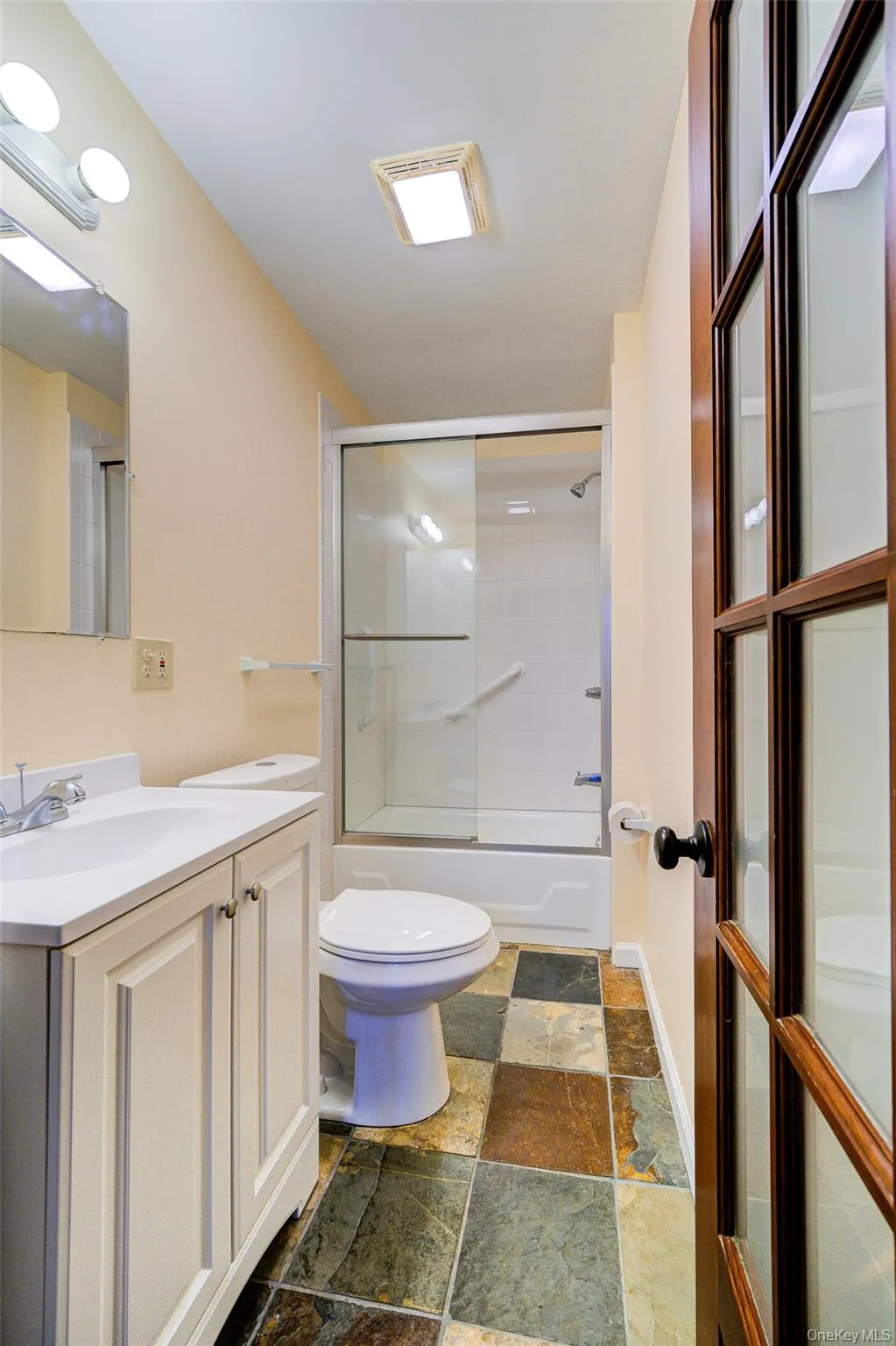 Full bathroom with toilet, vanity, and combined bath / shower with glass door Full bathroom with toilet, vanity, and combined bath / shower with glass door