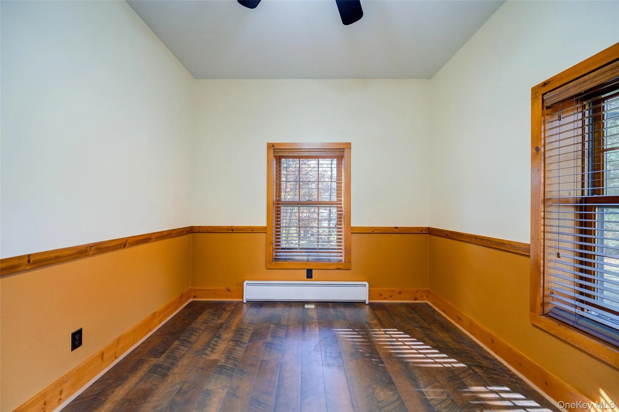 Unfurnished room featuring dark hardwood / wood-style floors, ceiling fan, and a baseboard heating unit Unfurnished room featuring dark hardwood / wood-style floors, ceiling fan, and a baseboard heating unit