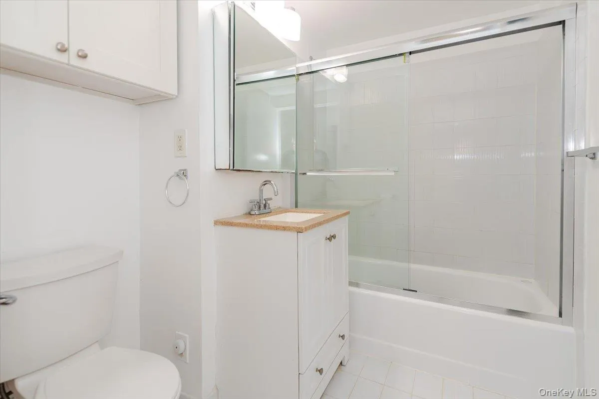 Full bathroom featuring vanity, combined bath / shower with glass door, and tile patterned floors Full bathroom featuring vanity, combined bath / shower with glass door, and tile patterned floors