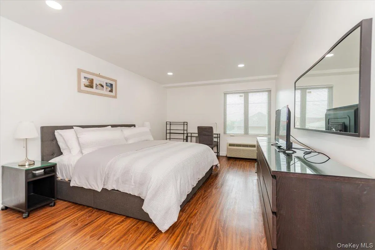 Bedroom with wood finished floors, recessed lighting, and radiator heating unit Bedroom with wood finished floors, recessed lighting, and radiator heating unit