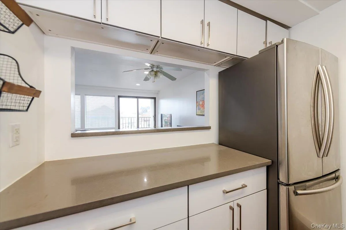 Kitchen with freestanding refrigerator, white cabinetry, ceiling fan, and dark countertops Kitchen with freestanding refrigerator, white cabinetry, ceiling fan, and dark countertops