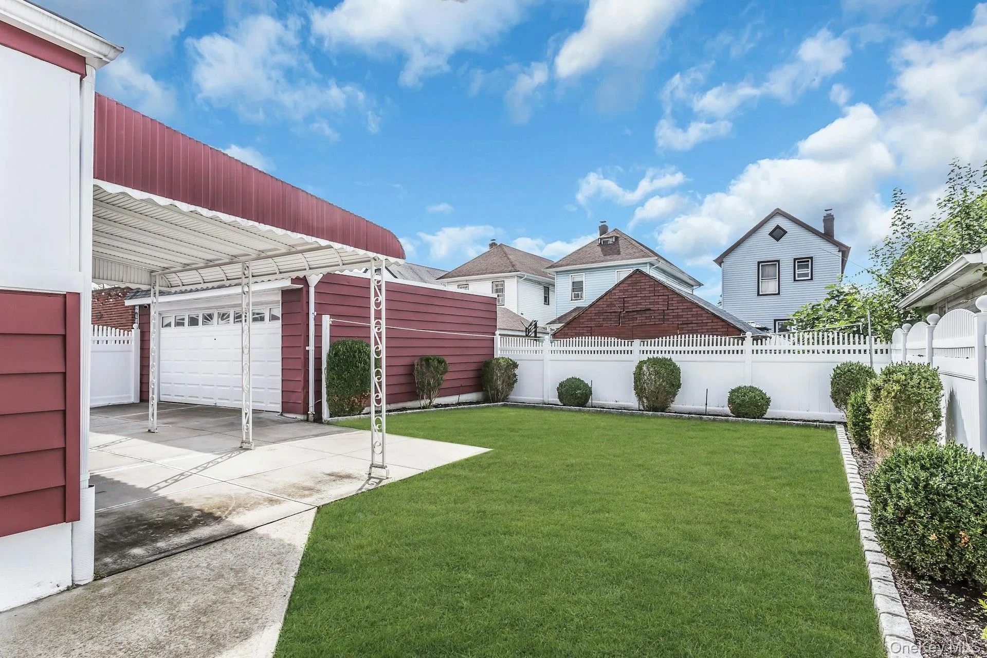Expansive backyard featuring a manicured lawn, white picket fencing, and mature shrubbery Expansive backyard featuring a manicured lawn, white picket fencing, and mature shrubbery
