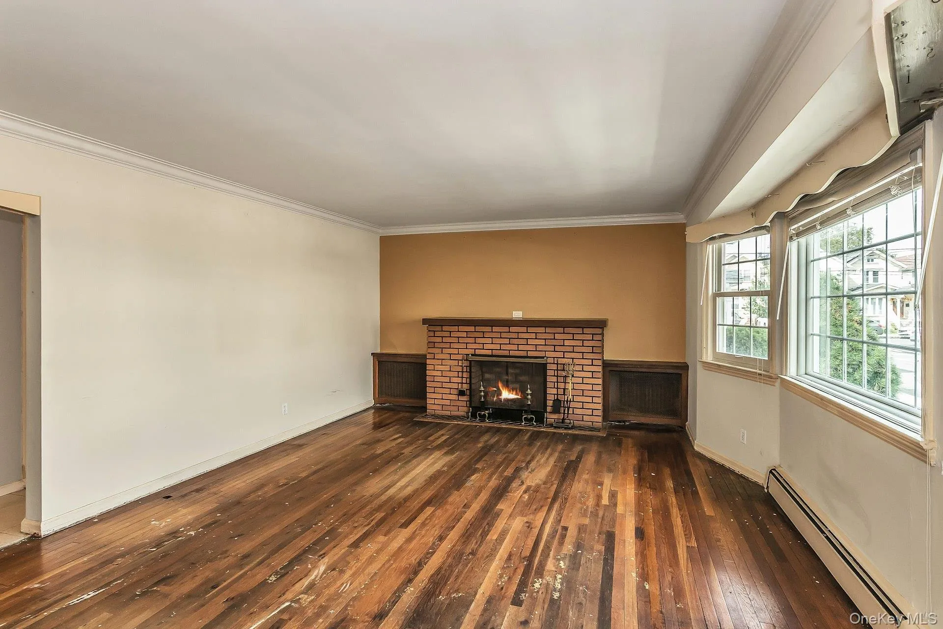 Hardwood flooring, brick fireplace with a wood mantel, crown molding, and a bay window Hardwood flooring, brick fireplace with a wood mantel, crown molding, and a bay window
