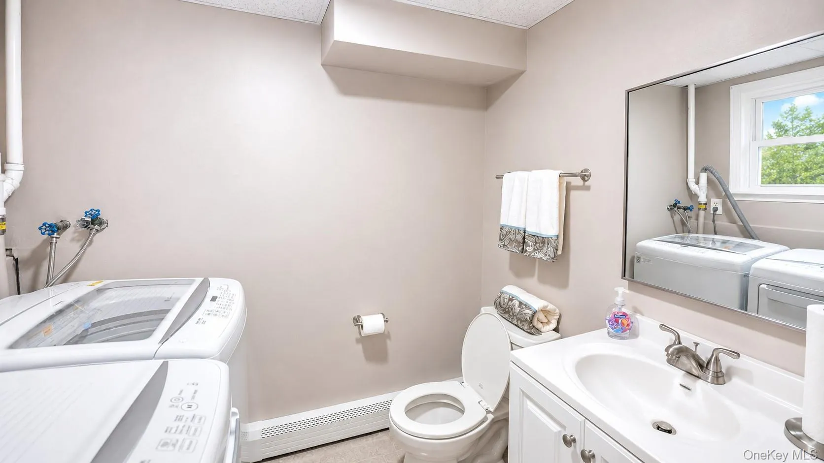 White vanity with a basin sink and brushed nickel faucet, large wall mirror, and a window White vanity with a basin sink and brushed nickel faucet, large wall mirror, and a window