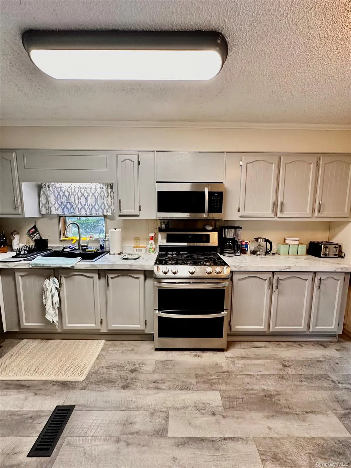 Kitchen featuring wood-finish flooring, light-toned cabinetry, stainless steel range, and built-in microwave Kitchen featuring wood-finish flooring, light-toned cabinetry, stainless steel range, and built-in microwave