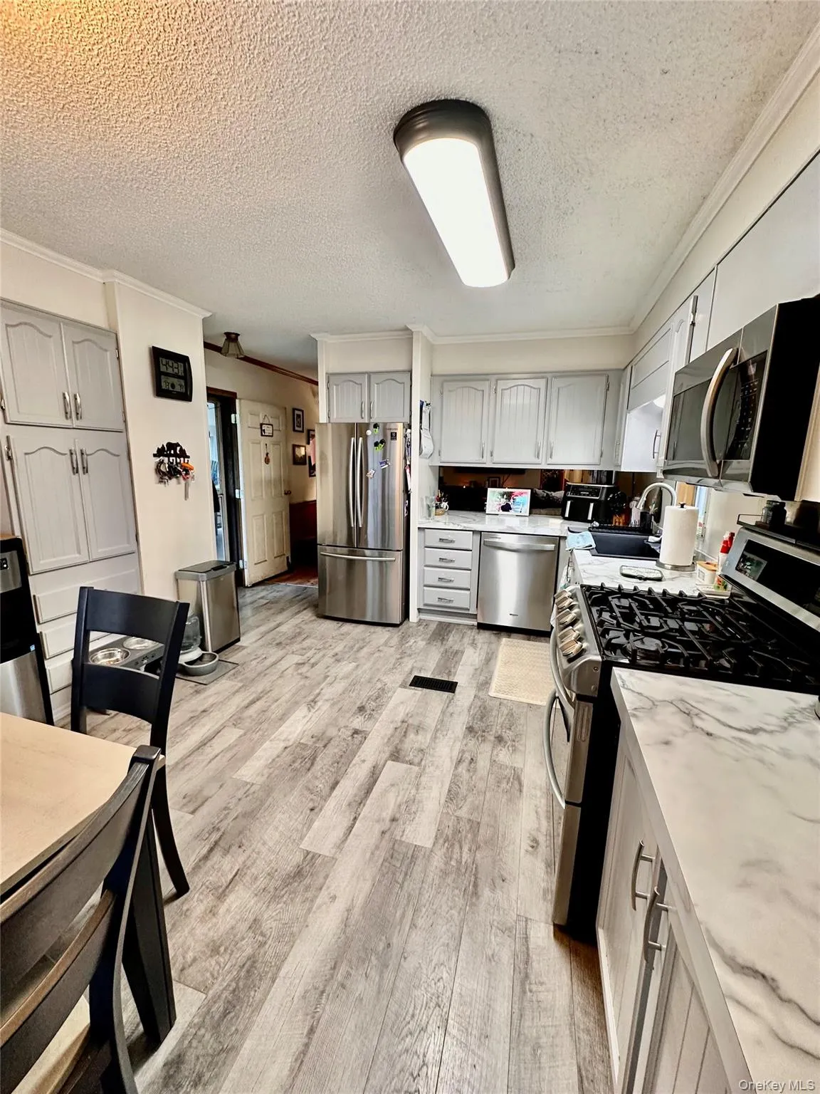 Wood-finish flooring, stainless steel appliances, light-toned cabinetry, and a gas range. Wood-finish flooring, stainless steel appliances, light-toned cabinetry, and a gas range.