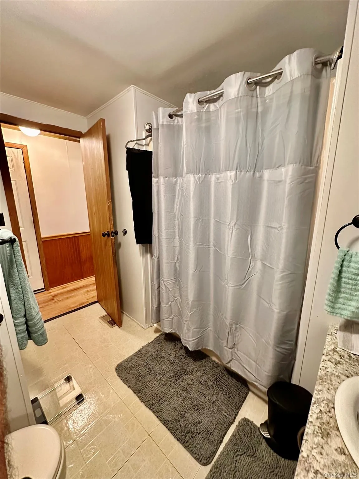 Shower with a stainless steel curtain rod, a white toilet, and a light-colored tile floor. Shower with a stainless steel curtain rod, a white toilet, and a light-colored tile floor.
