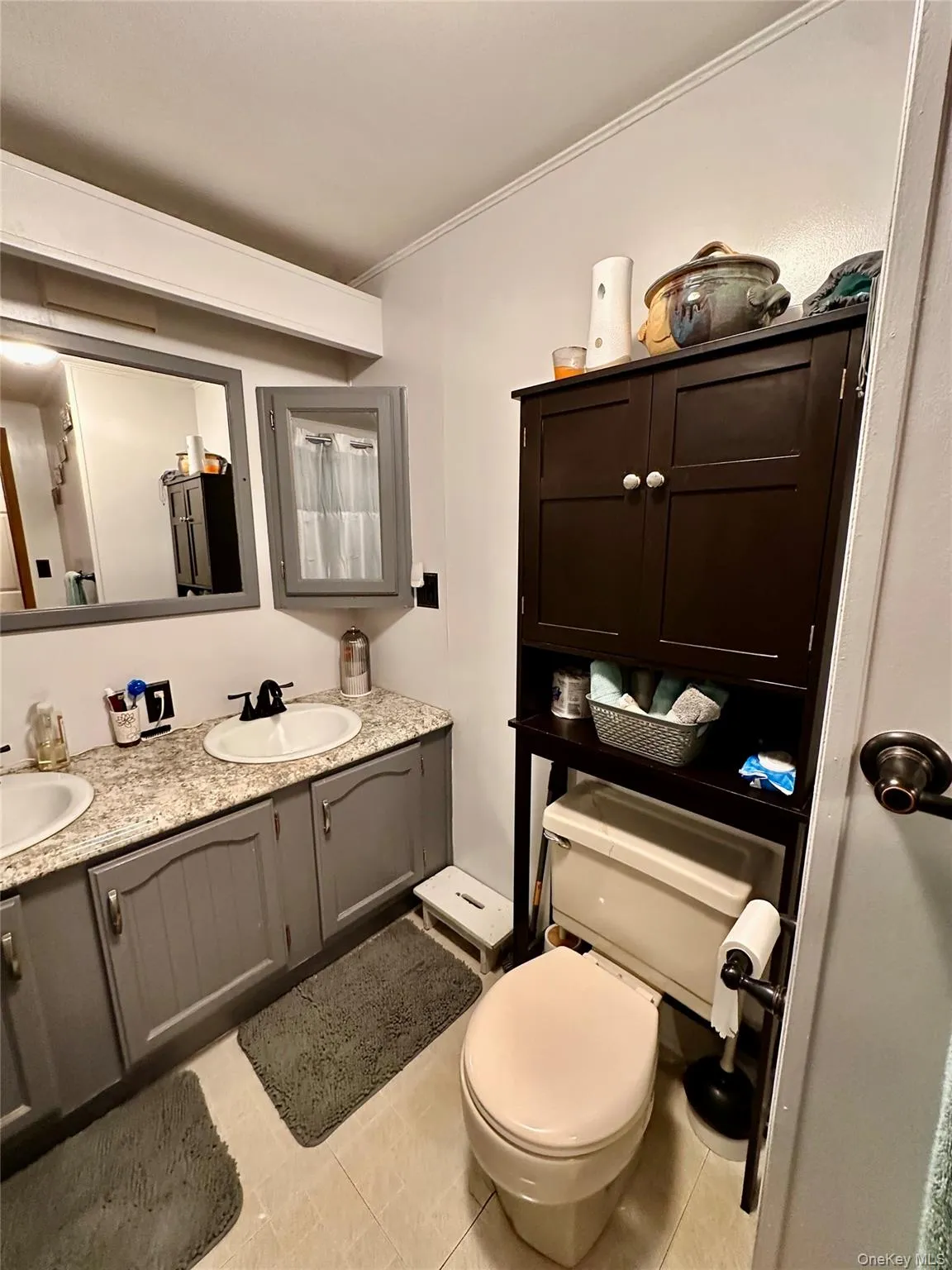 Dual vanity with integrated sinks and gray cabinetry, complemented by a speckled countertop. Dual vanity with integrated sinks and gray cabinetry, complemented by a speckled countertop.