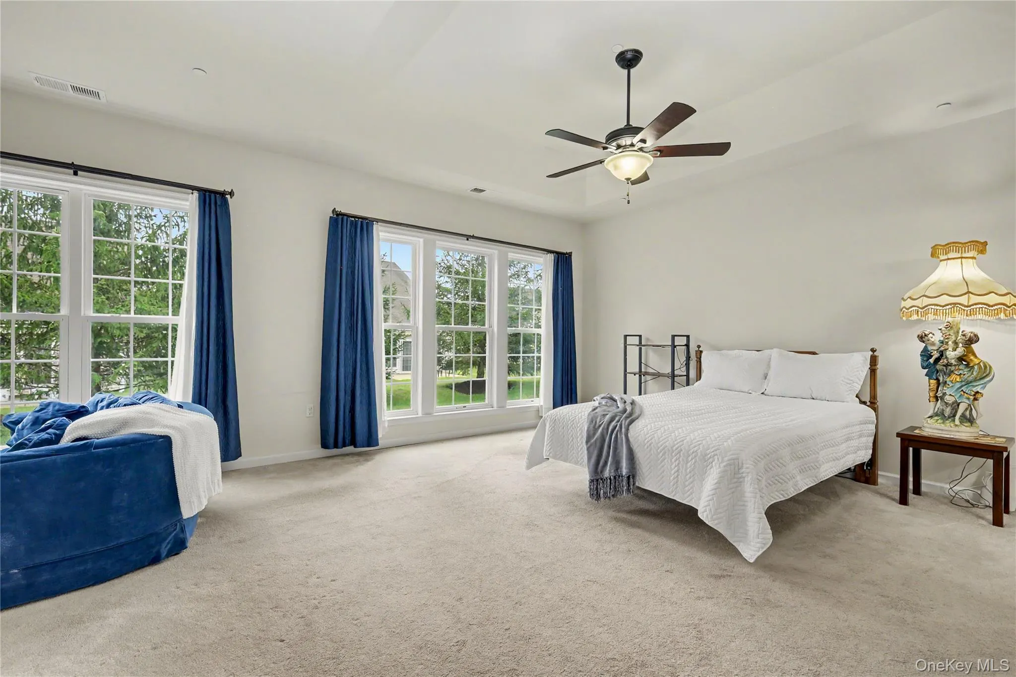 Carpeted flooring with multiple windows, a ceiling fan, and a neutral color palette Carpeted flooring with multiple windows, a ceiling fan, and a neutral color palette