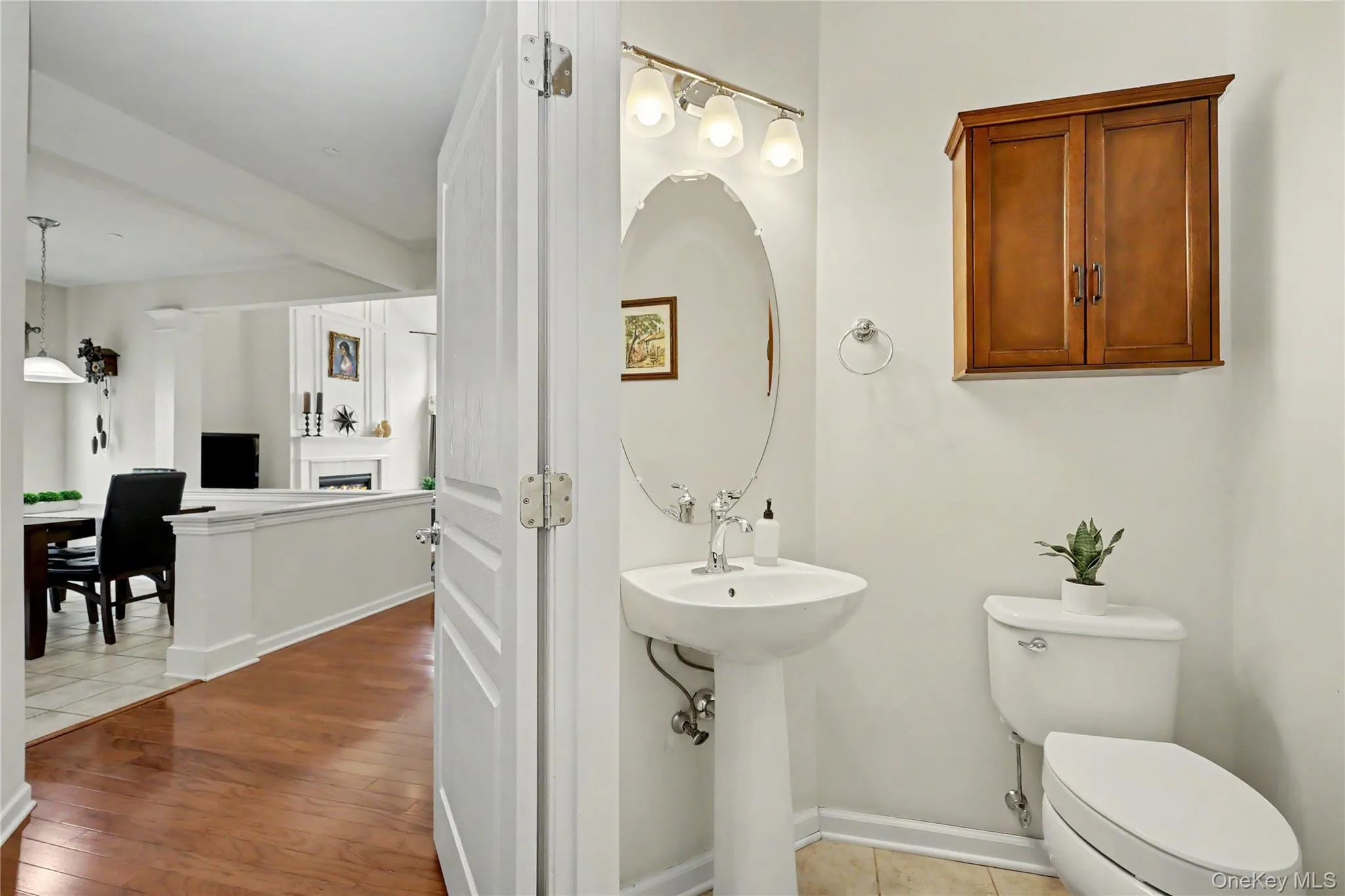 Pedestal sink with oval mirror and wall-mounted light fixture Pedestal sink with oval mirror and wall-mounted light fixture
