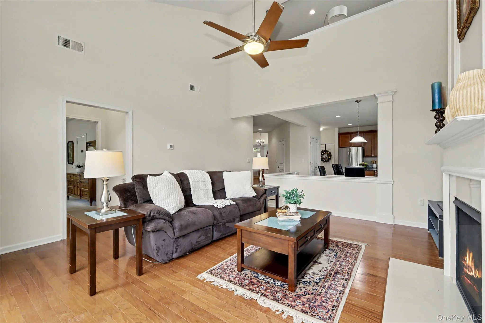 Vaulted ceilings, wood-finish flooring, ceiling fan with integrated lighting, fireplace, and a pass-through opening to the kitchen Vaulted ceilings, wood-finish flooring, ceiling fan with integrated lighting, fireplace, and a pass-through opening to the kitchen