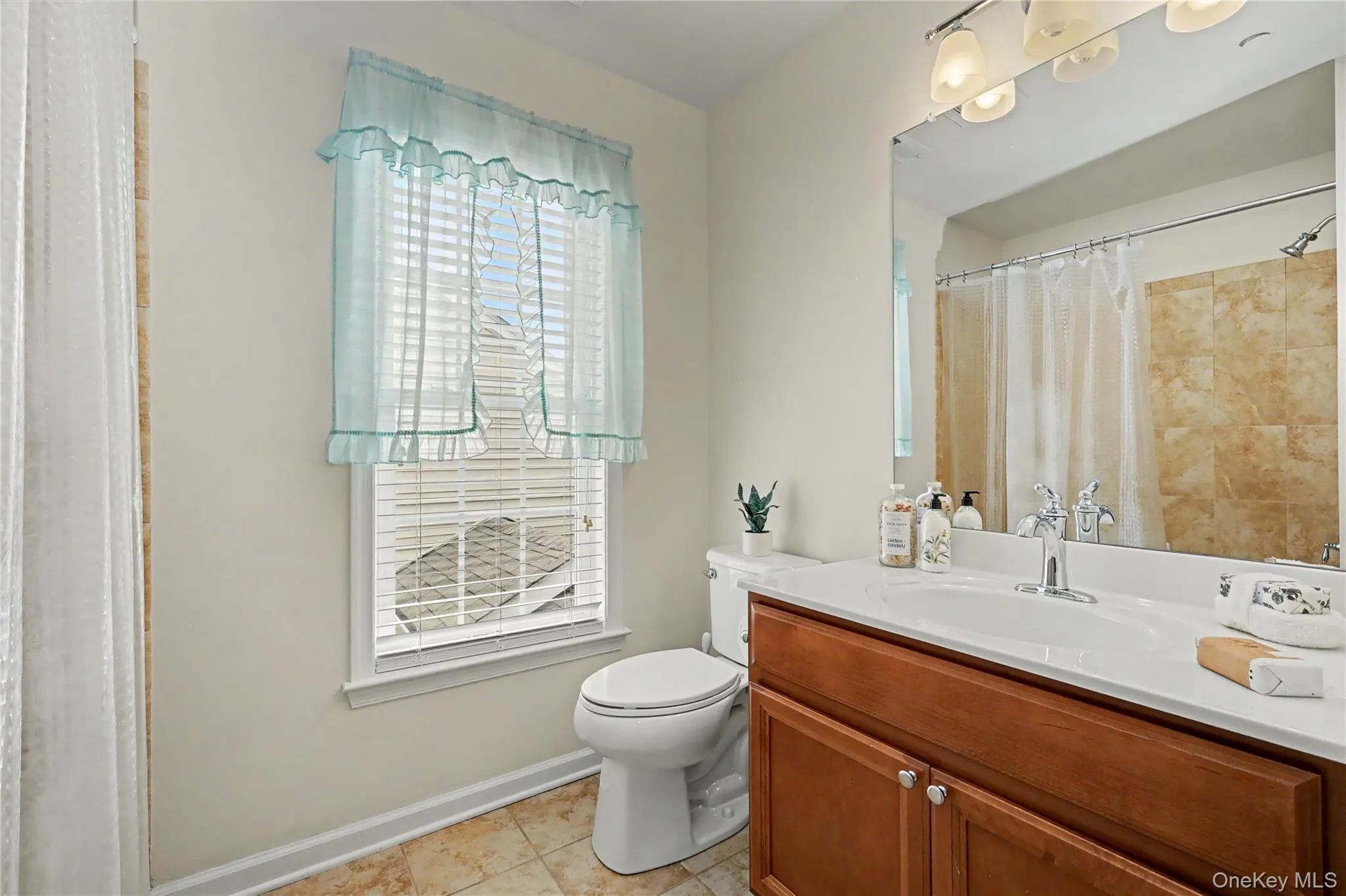 Hardwood-finish vanity with an integrated sink, polished chrome faucet, and expansive wall-mounted mirror Hardwood-finish vanity with an integrated sink, polished chrome faucet, and expansive wall-mounted mirror