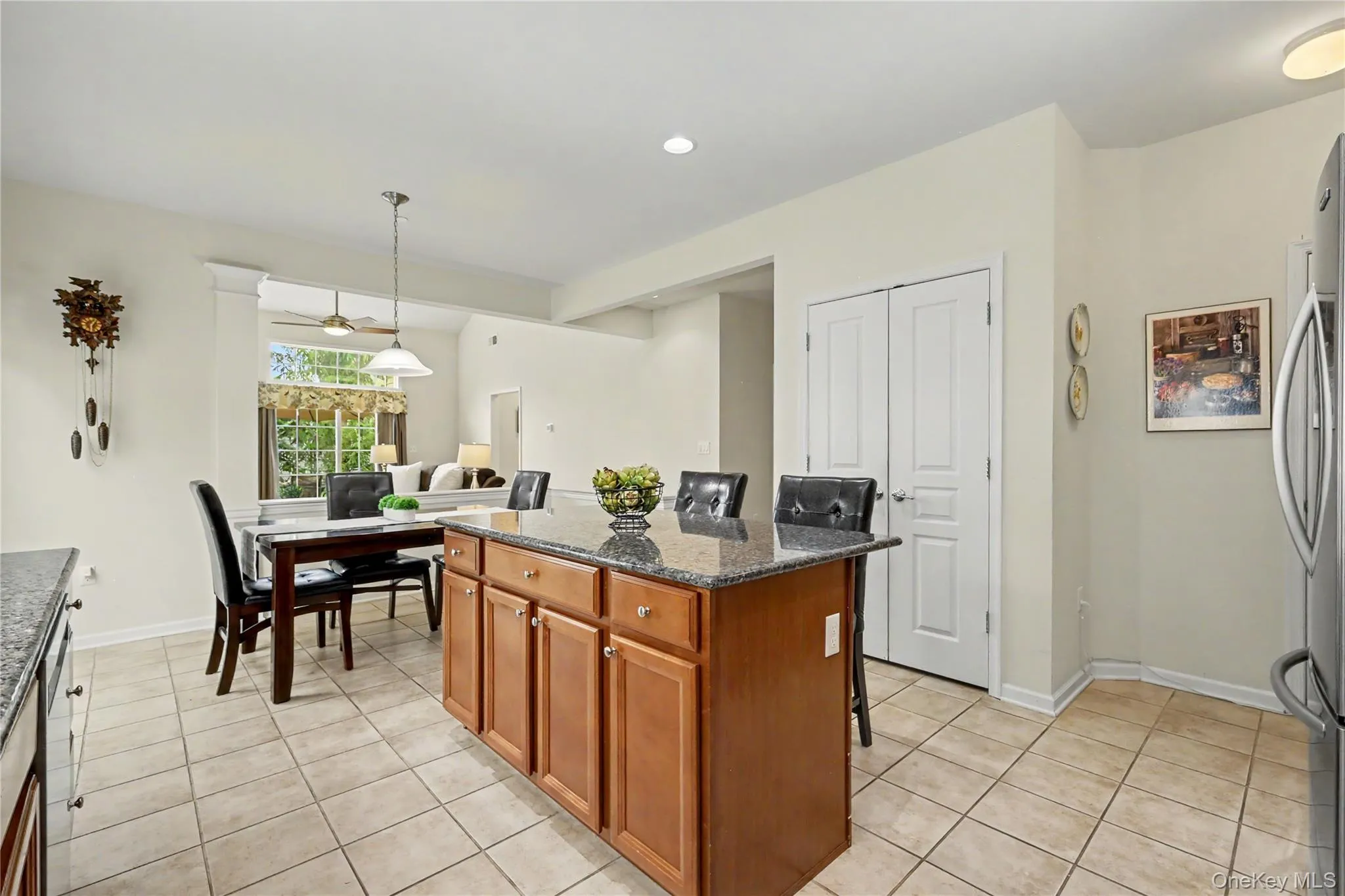 Kitchen island with wood cabinetry, granite countertop, and tile flooring Kitchen island with wood cabinetry, granite countertop, and tile flooring