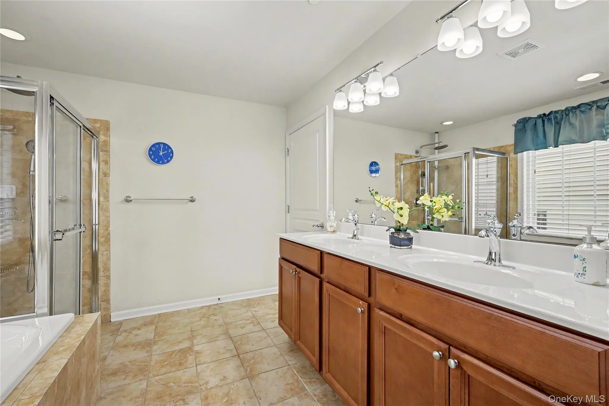 Dual vanity with white countertops, chrome fixtures, and wood-finish cabinetry Dual vanity with white countertops, chrome fixtures, and wood-finish cabinetry