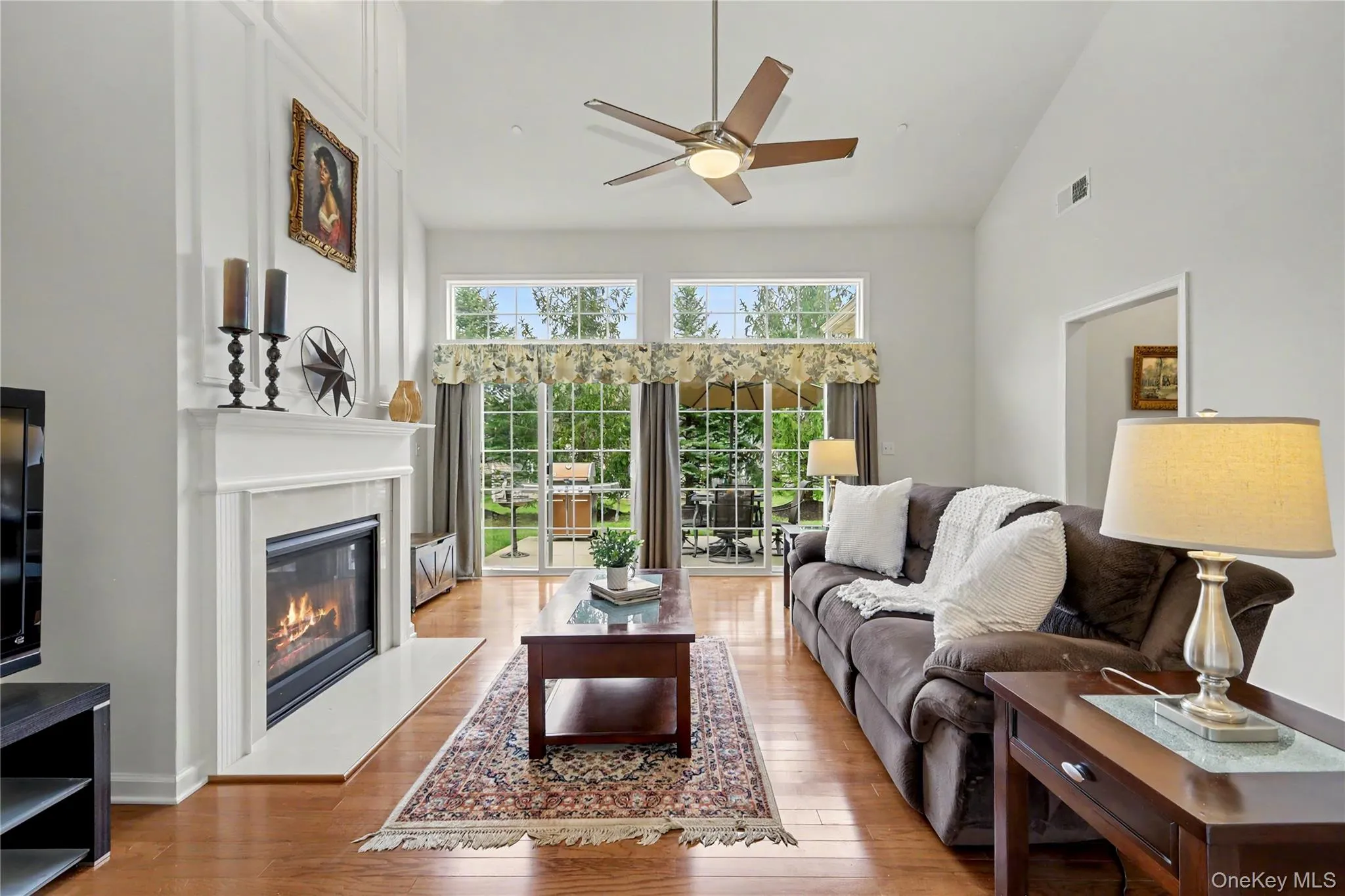 Vaulted ceiling with ceiling fan, wood-finish flooring, fireplace with mantel, and sliding glass doors Vaulted ceiling with ceiling fan, wood-finish flooring, fireplace with mantel, and sliding glass doors
