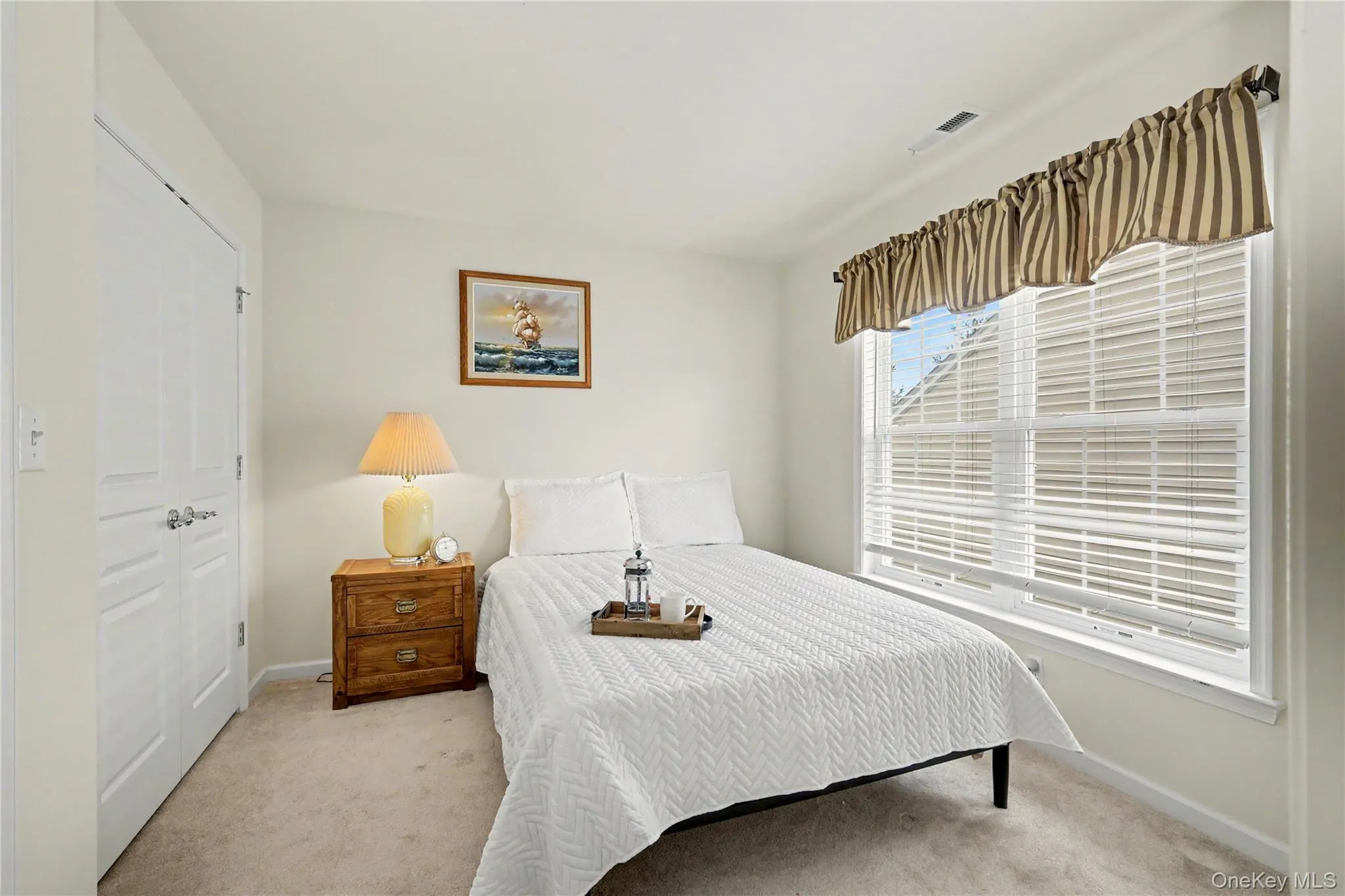 Neutral tone wall finishes, double window with horizontal blinds, neutral tone carpeting, and a closet Neutral tone wall finishes, double window with horizontal blinds, neutral tone carpeting, and a closet