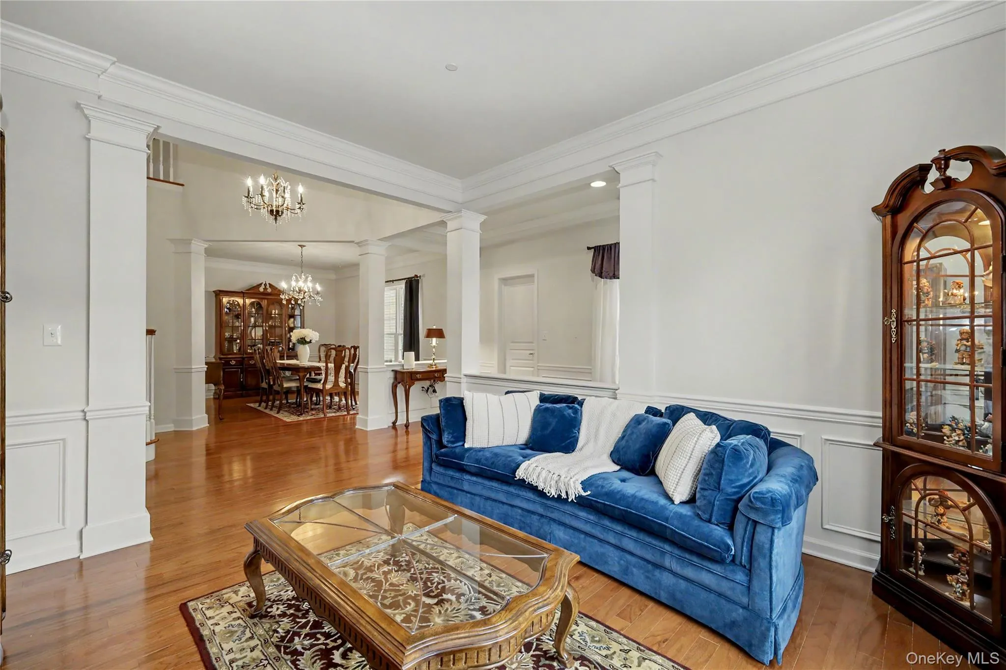 Wood-finish flooring throughout, substantial crown molding, wainscoting details, and column accents frame the open interior Wood-finish flooring throughout, substantial crown molding, wainscoting details, and column accents frame the open interior