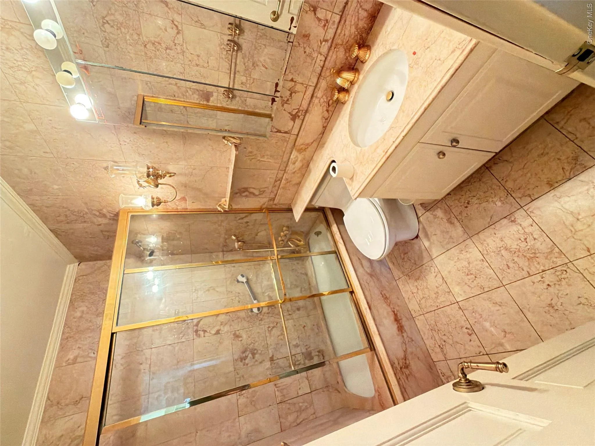 Bathroom featuring a vanity with a drop-in sink, gold-finish fixtures, and a shower-tub combination with sliding glass doors Bathroom featuring a vanity with a drop-in sink, gold-finish fixtures, and a shower-tub combination with sliding glass doors