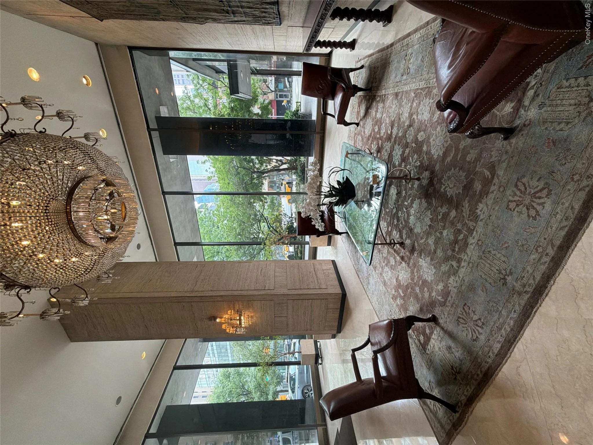 Floor-to-ceiling windows, recessed ceiling lighting, a prominent crystal chandelier, and polished stone flooring Floor-to-ceiling windows, recessed ceiling lighting, a prominent crystal chandelier, and polished stone flooring