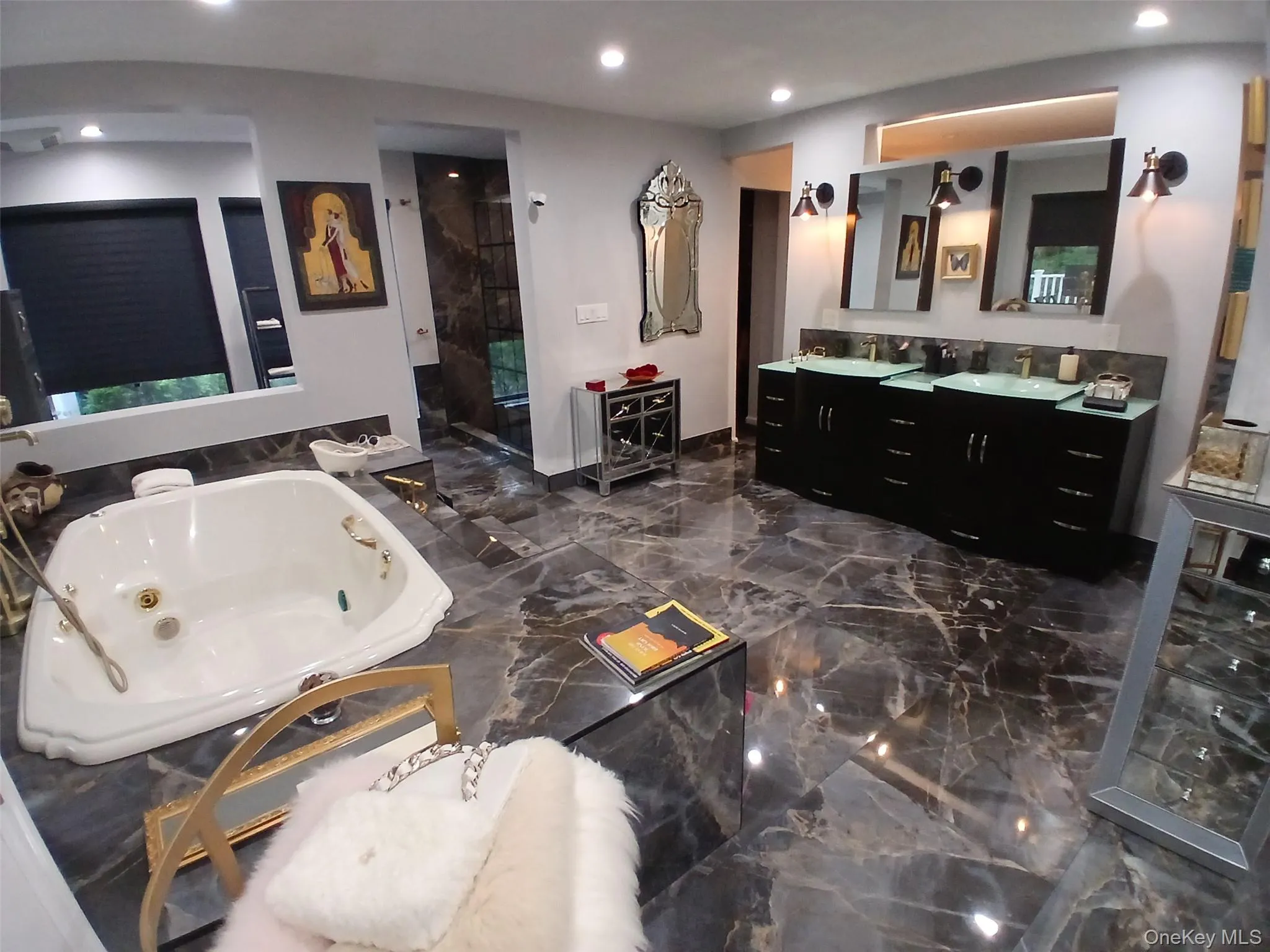 Jacuzzi tub with a surround, dual vanities with integrated sinks, built-in shower, and marble-finish flooring Jacuzzi tub with a surround, dual vanities with integrated sinks, built-in shower, and marble-finish flooring