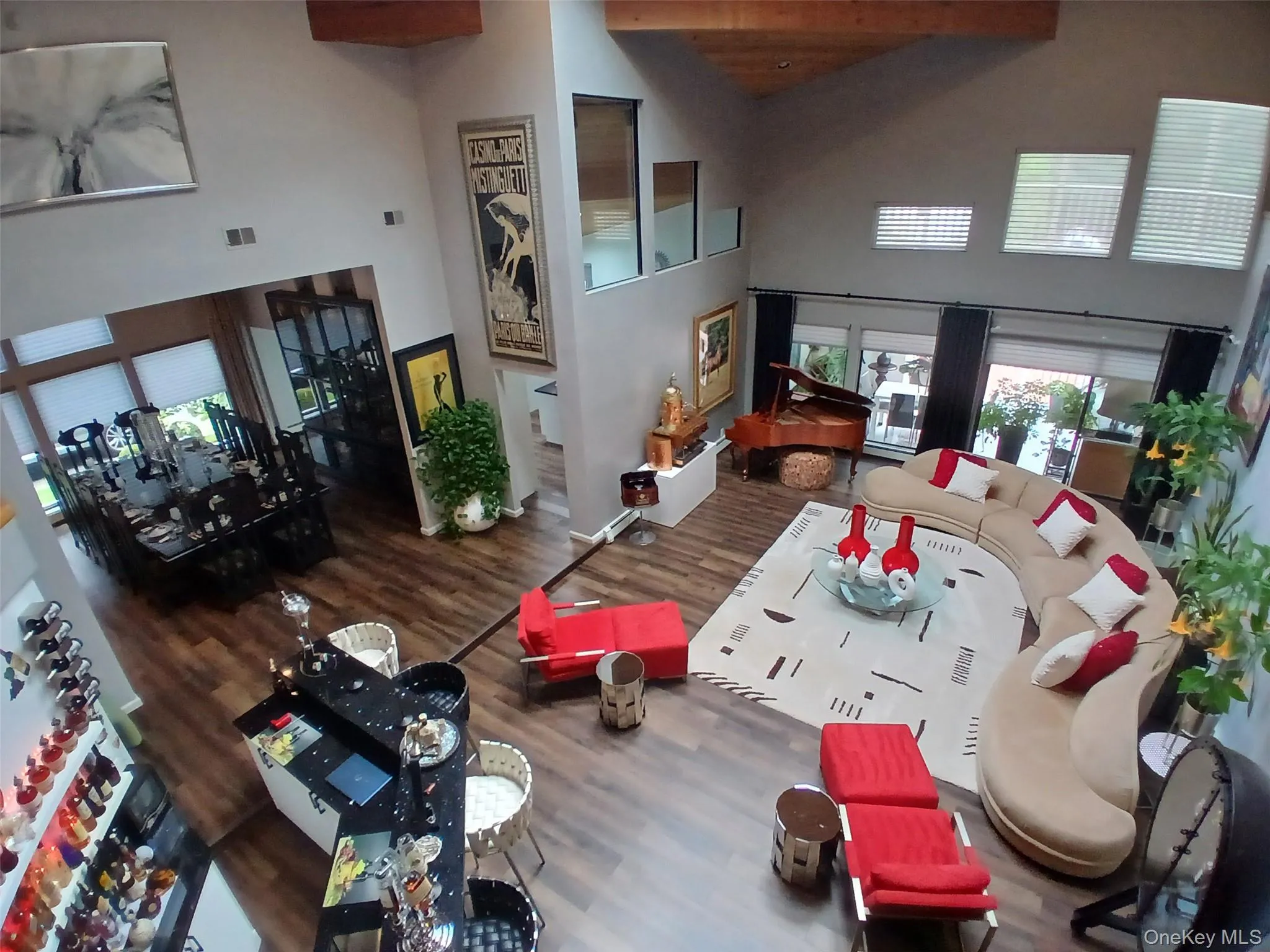 Vaulted ceiling with exposed wood beam, wood-finish flooring, built-in bar, and multiple large windows Vaulted ceiling with exposed wood beam, wood-finish flooring, built-in bar, and multiple large windows