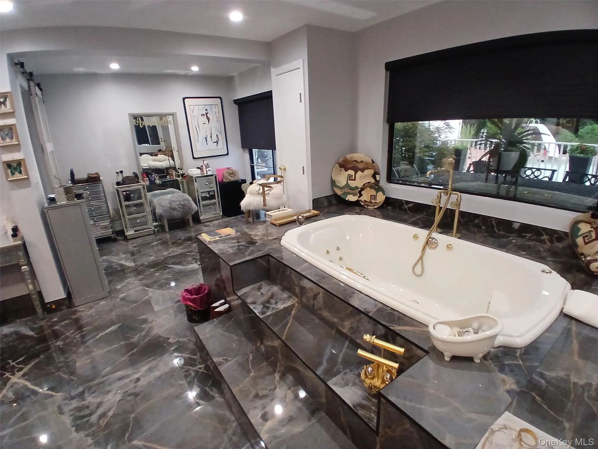 Spa-style jetted tub with gold-finish fixtures, set within a tiered, dark marble-finish surround Spa-style jetted tub with gold-finish fixtures, set within a tiered, dark marble-finish surround