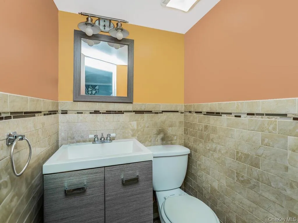 Bathroom featuring vanity, tile walls, and toilet Bathroom featuring vanity, tile walls, and toilet