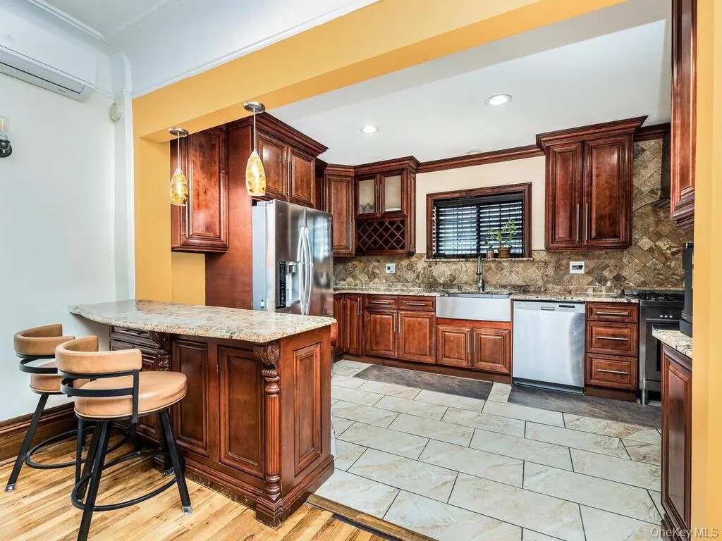 Kitchen featuring tasteful backsplash, stainless steel appliances, sink, light stone counters, and light wood-type flooring Kitchen featuring tasteful backsplash, stainless steel appliances, sink, light stone counters, and light wood-type flooring