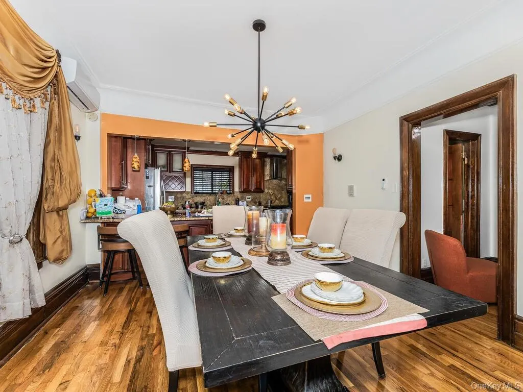 Dining room featuring a wall mounted air conditioner, dark hardwood / wood-style floors, and a chandelier Dining room featuring a wall mounted air conditioner, dark hardwood / wood-style floors, and a chandelier