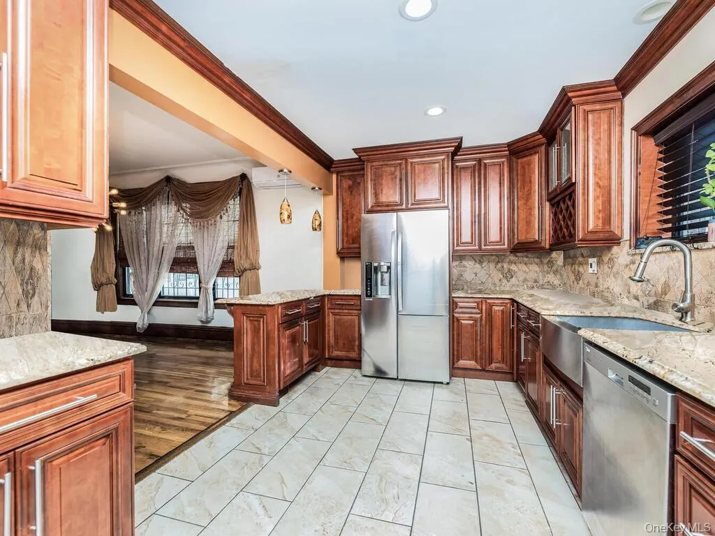 Kitchen featuring light hardwood / wood-style flooring, backsplash, light stone countertops, appliances with stainless steel finishes, and sink Kitchen featuring light hardwood / wood-style flooring, backsplash, light stone countertops, appliances with stainless steel finishes, and sink