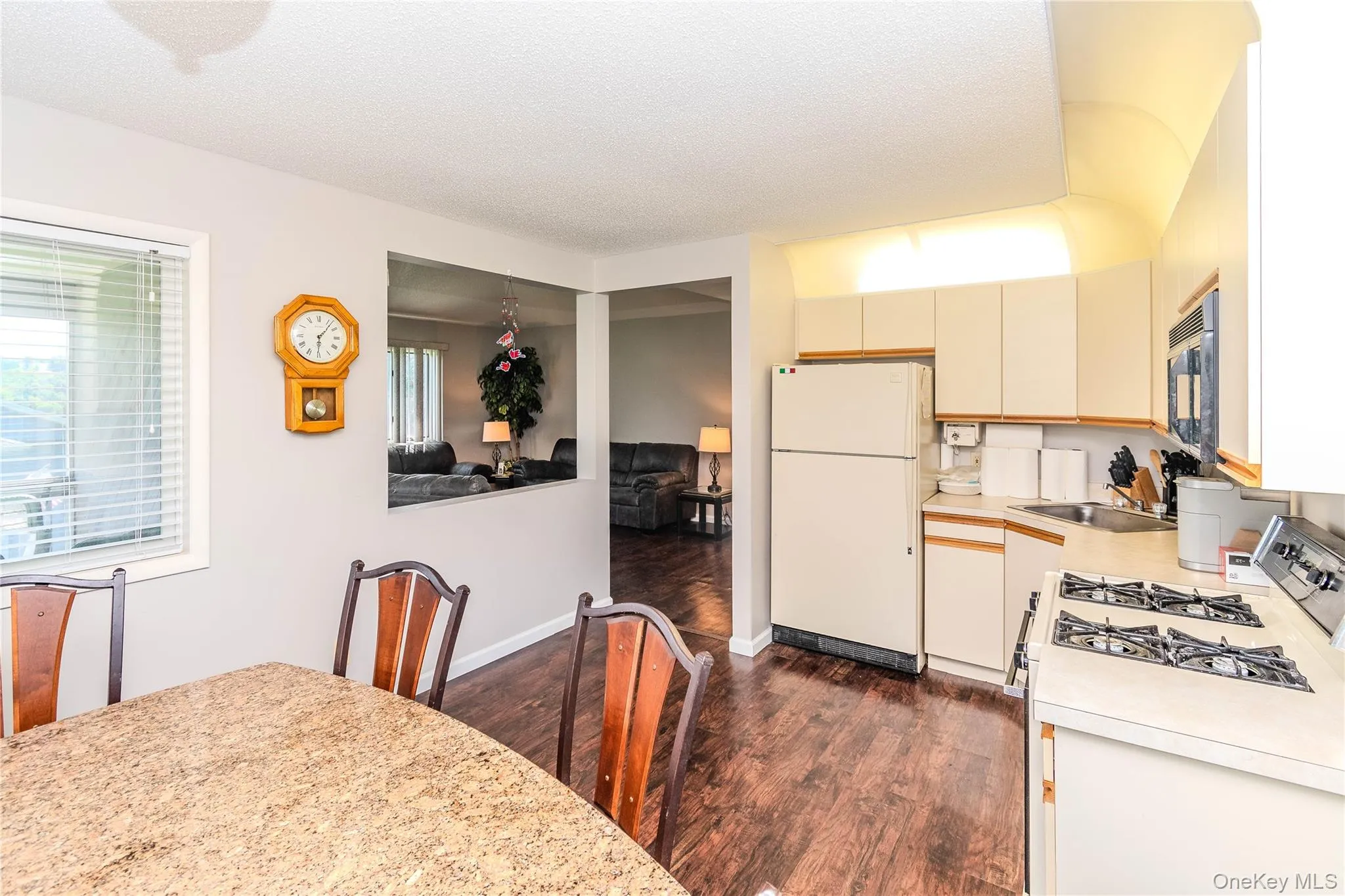 Kitchen featuring wood-finish flooring, white cabinetry, integrated sink, and an electric range Kitchen featuring wood-finish flooring, white cabinetry, integrated sink, and an electric range