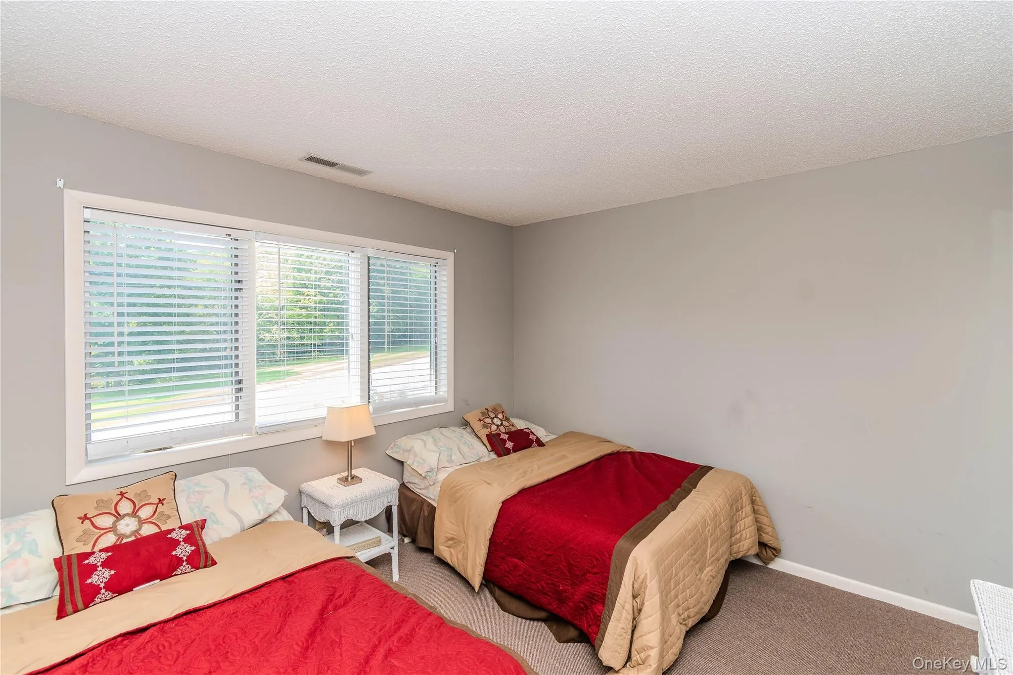 Triple window with white blinds, textured ceiling, gray painted walls, and gray carpeting Triple window with white blinds, textured ceiling, gray painted walls, and gray carpeting
