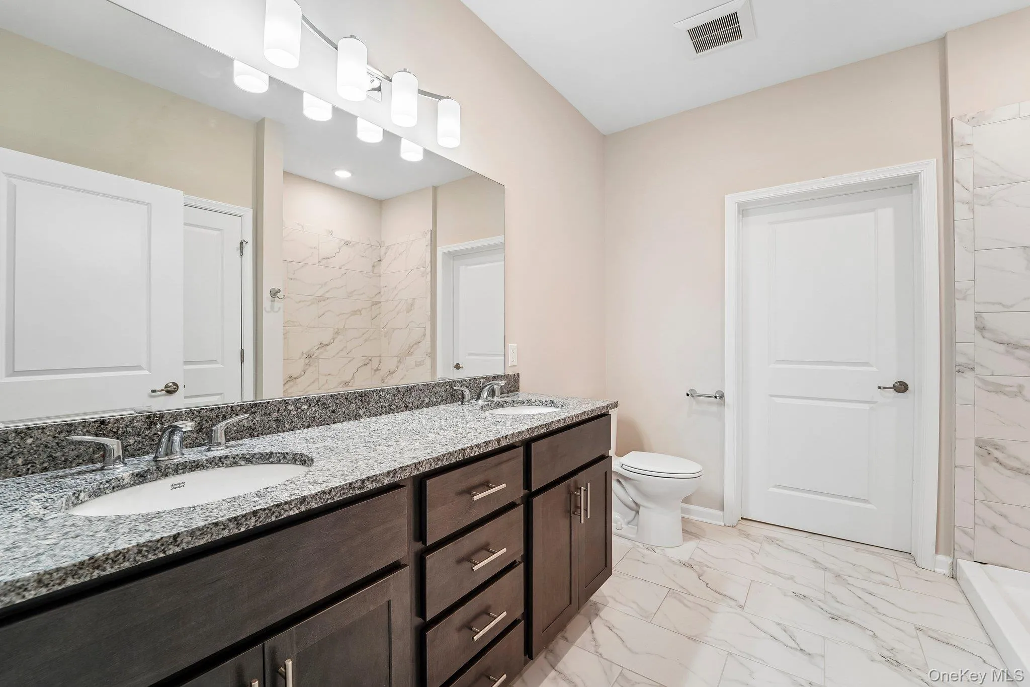 Double vanity with granite countertop, dual undermount sinks, and dark wood cabinetry Double vanity with granite countertop, dual undermount sinks, and dark wood cabinetry
