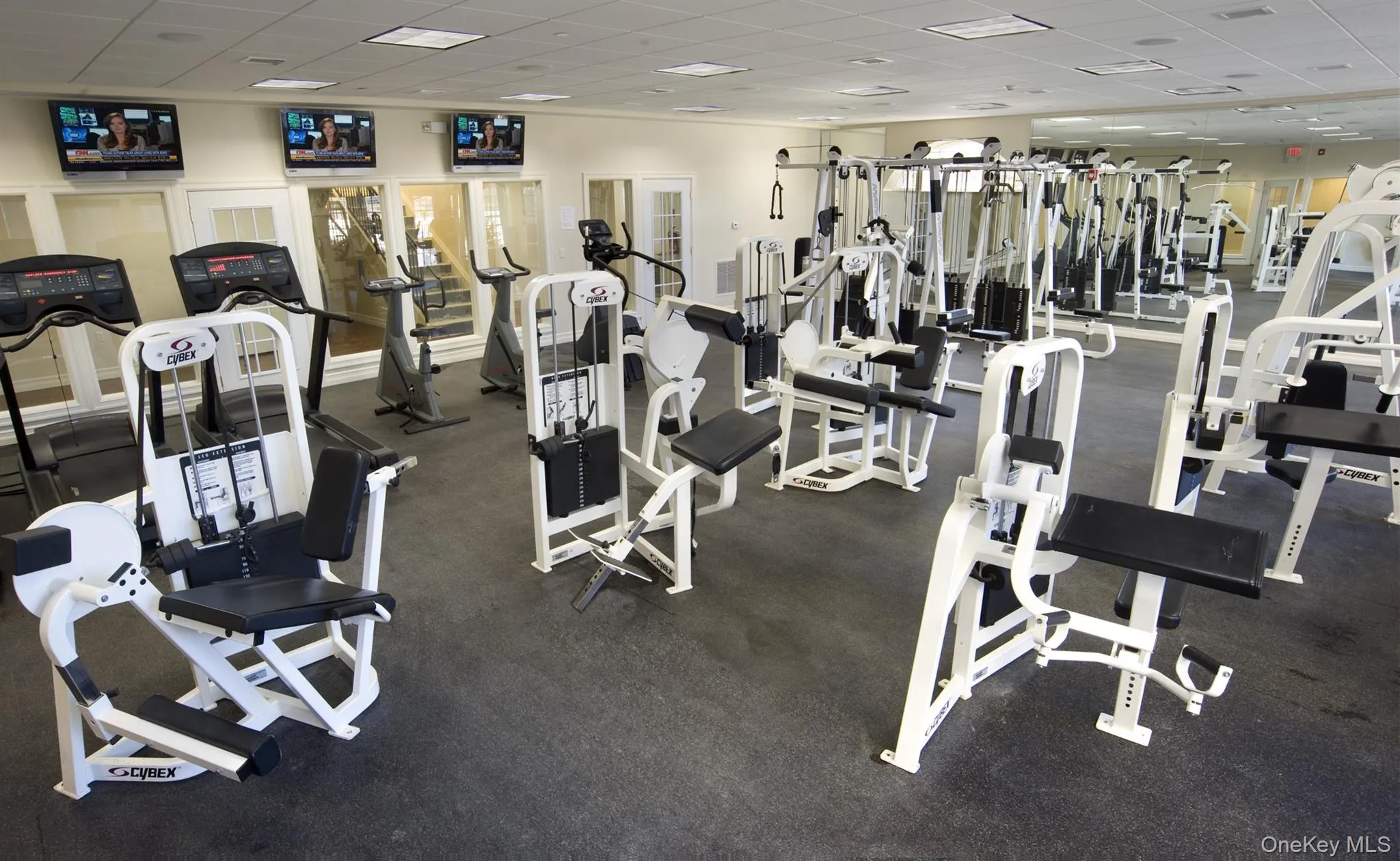Comprehensive fitness center featuring multiple strength training machines, cardio equipment, and durable floor surfacing Comprehensive fitness center featuring multiple strength training machines, cardio equipment, and durable floor surfacing