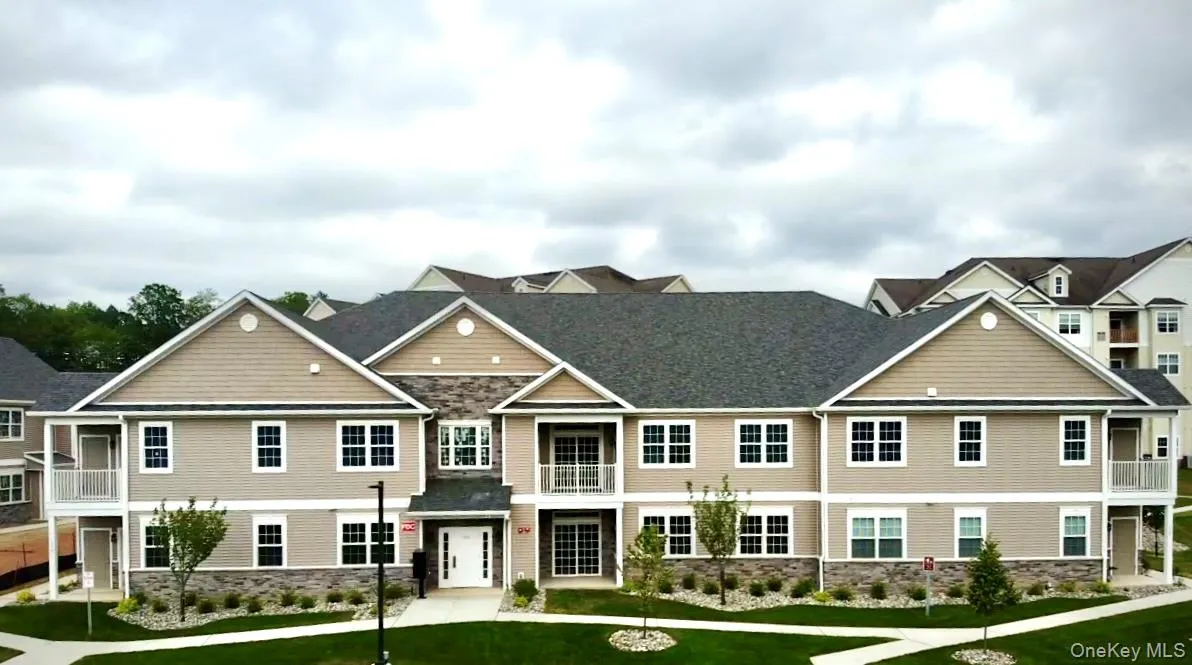 Multi-story building with gabled roofs, stone veneer accents, and multiple balconies Multi-story building with gabled roofs, stone veneer accents, and multiple balconies
