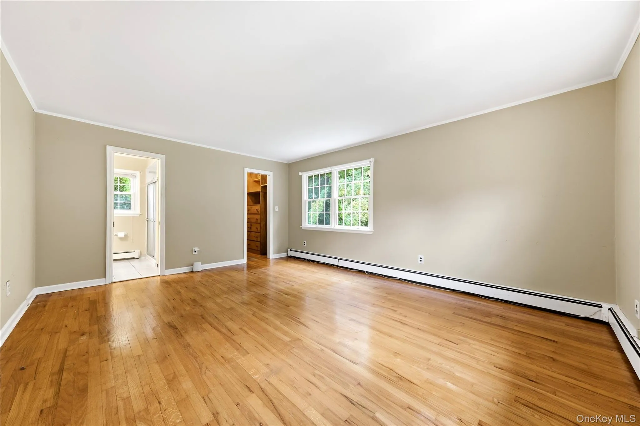 Primary bedroom with hardwood flooring, primary bathroom and walk in closet Primary bedroom with hardwood flooring, primary bathroom and walk in closet