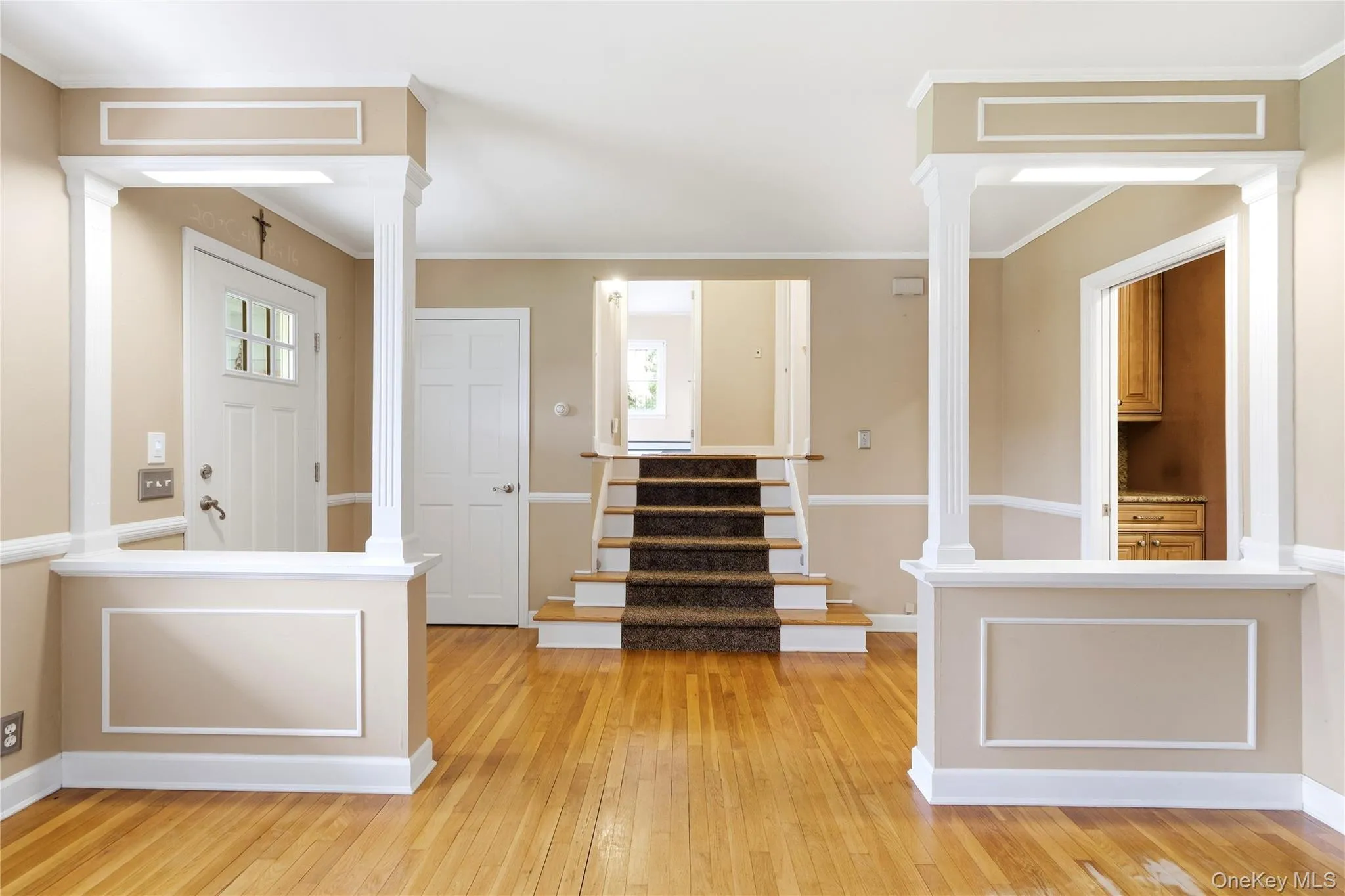 Hardwood flooring, painted walls, white trim, recessed paneling, and a staircase with carpeted treads Hardwood flooring, painted walls, white trim, recessed paneling, and a staircase with carpeted treads