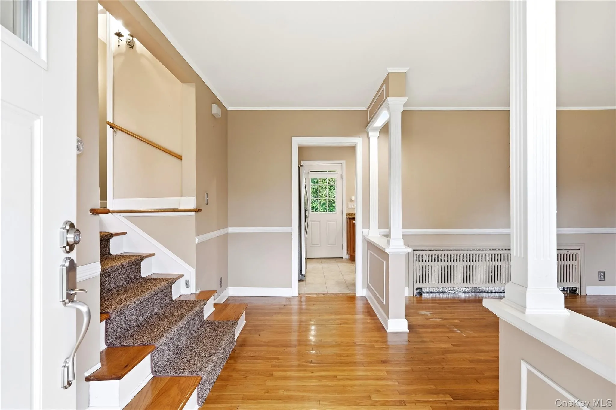 Wood-finish flooring, staircase with carpeted treads, classic white trim, and radiator heating Wood-finish flooring, staircase with carpeted treads, classic white trim, and radiator heating