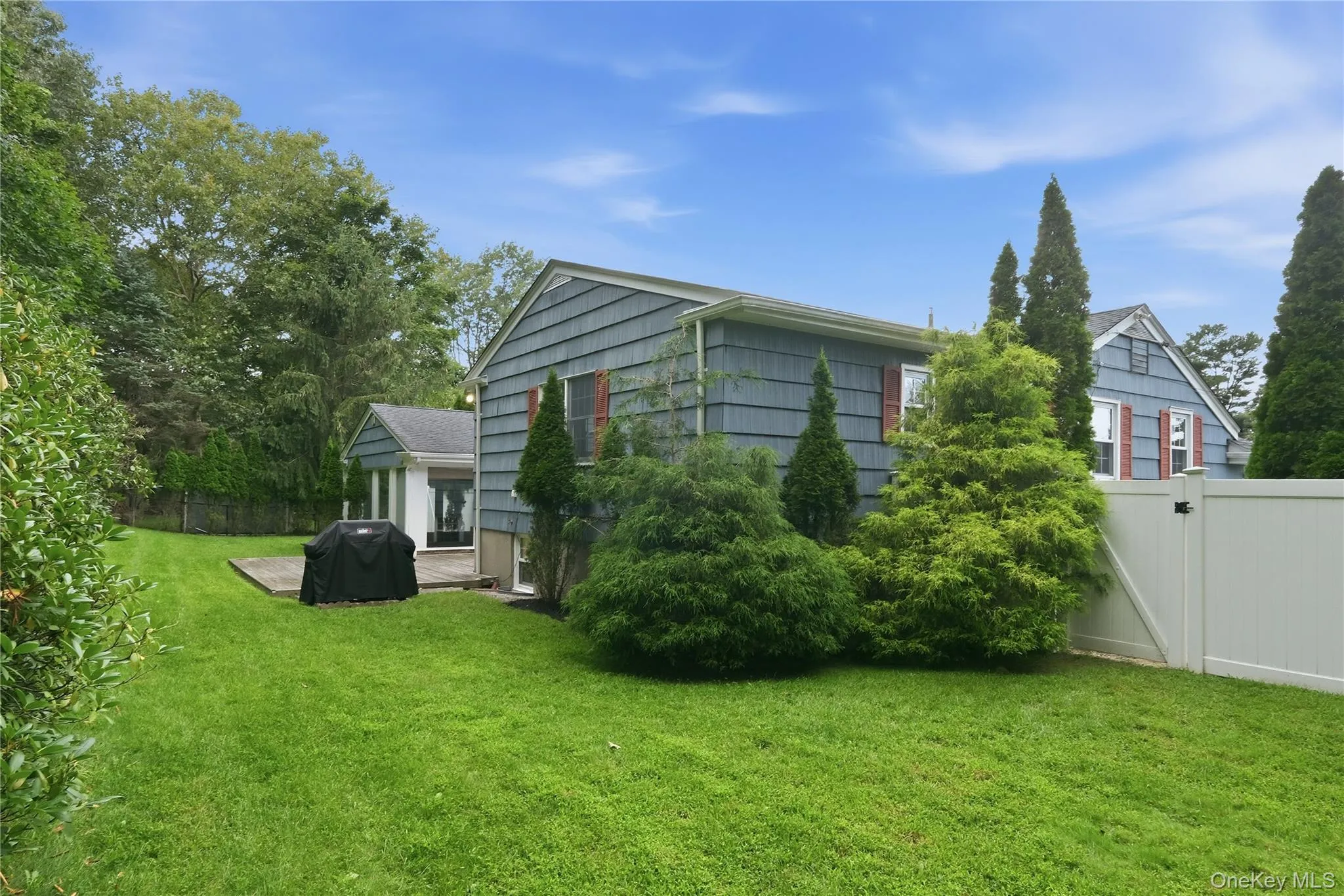 Expansive green lawn with mature landscaping, a private fence, and a patio area Expansive green lawn with mature landscaping, a private fence, and a patio area