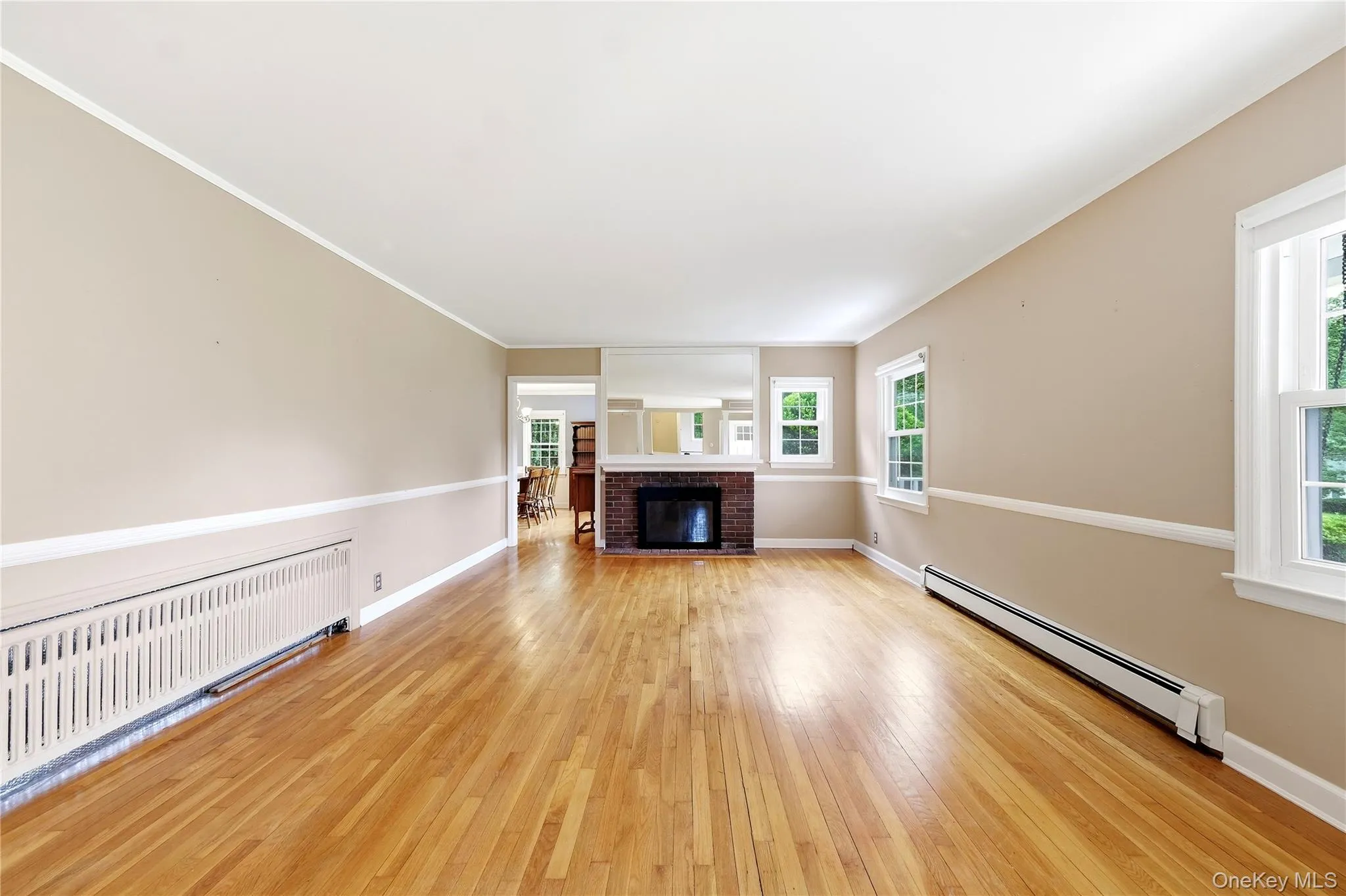 Hardwood flooring throughout, brick fireplace with a white mantel, multiple windows for ample light, and painted interior walls Hardwood flooring throughout, brick fireplace with a white mantel, multiple windows for ample light, and painted interior walls