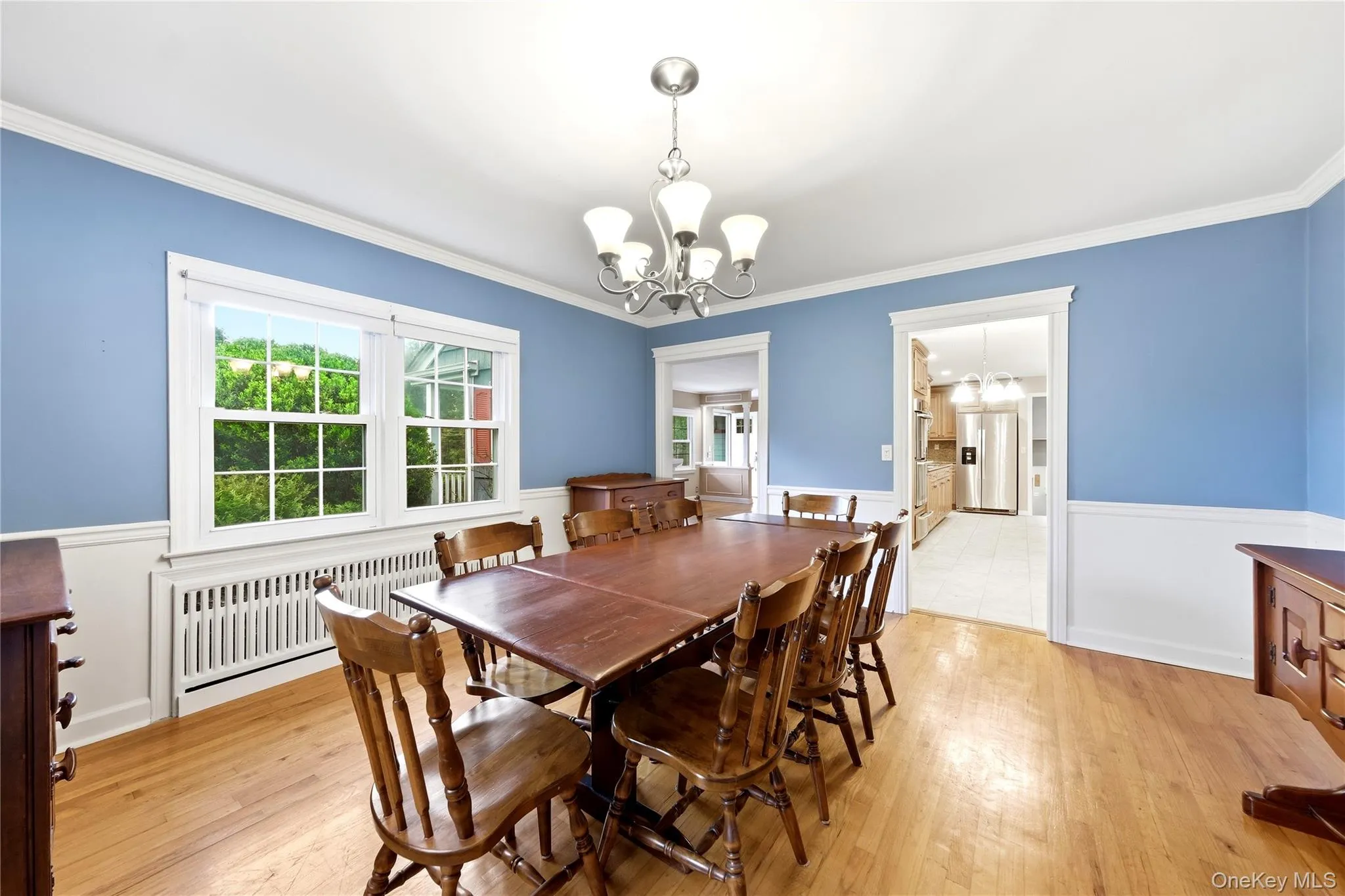 Hardwood flooring, white crown molding, white wainscoting, and a multi-arm chandelier Hardwood flooring, white crown molding, white wainscoting, and a multi-arm chandelier
