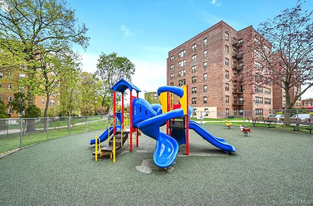 Community playground featuring a multi-color play structure with slides and climbing elements, spring riders, and a soft-fall surface Community playground featuring a multi-color play structure with slides and climbing elements, spring riders, and a soft-fall surface