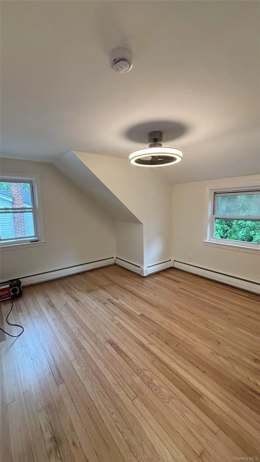 Additional living space featuring plenty of natural light, light wood finished floors, lofted ceiling, and baseboard heating Additional living space featuring plenty of natural light, light wood finished floors, lofted ceiling, and baseboard heating