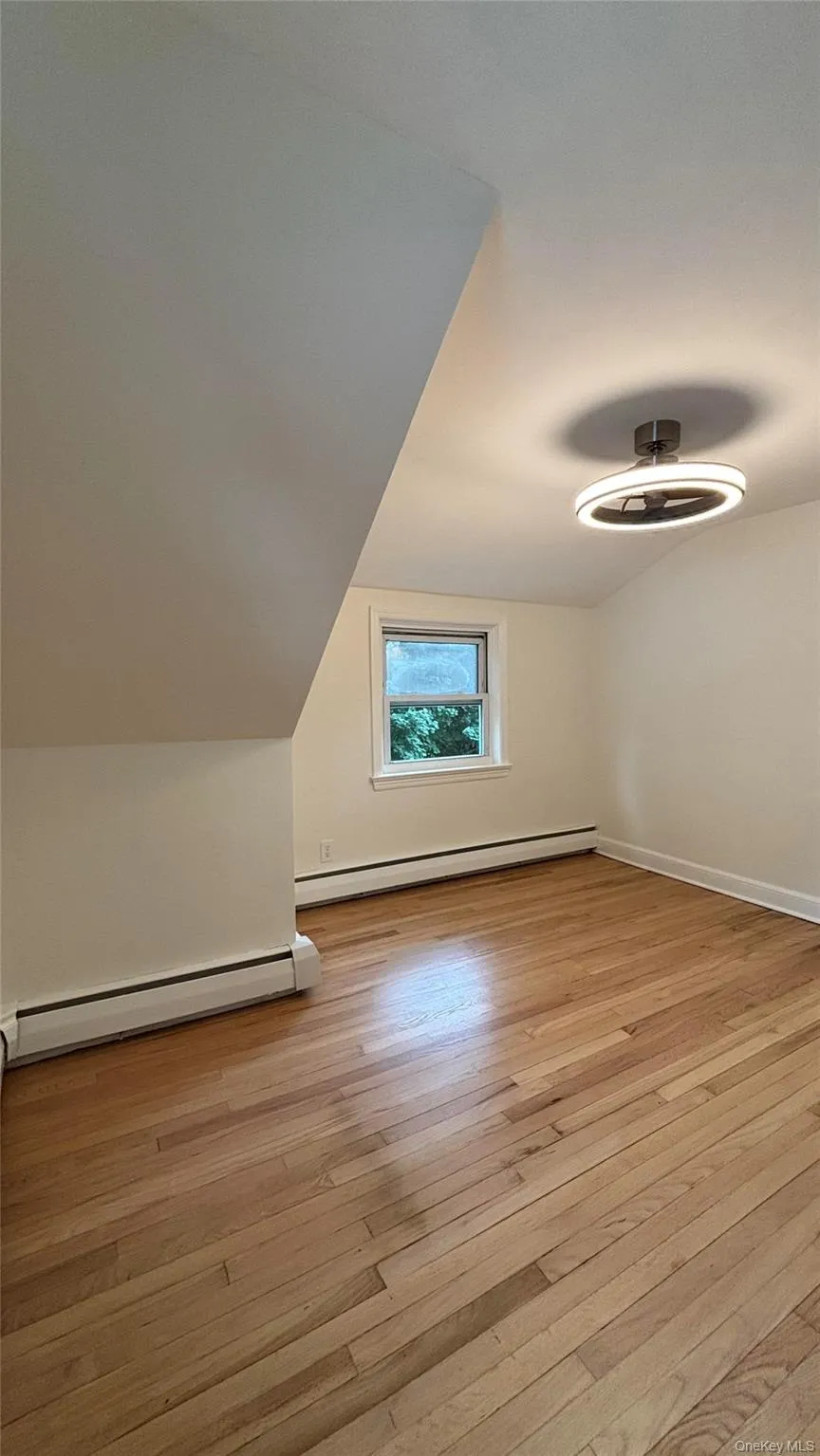 Additional living space featuring a baseboard heating unit, light wood-style floors, and lofted ceiling Additional living space featuring a baseboard heating unit, light wood-style floors, and lofted ceiling