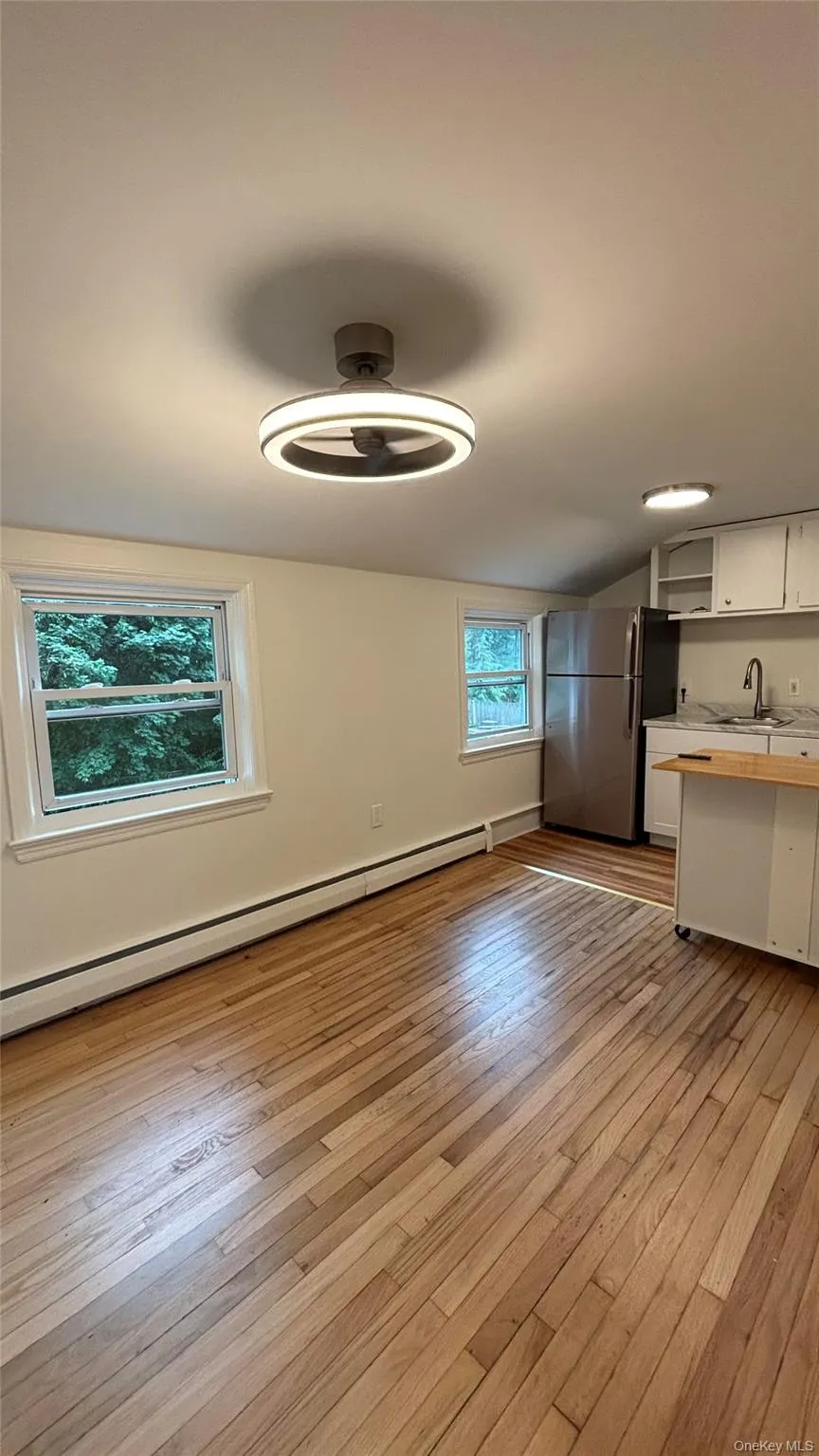 Unfurnished dining area featuring a baseboard radiator, light wood-style flooring, and vaulted ceiling Unfurnished dining area featuring a baseboard radiator, light wood-style flooring, and vaulted ceiling