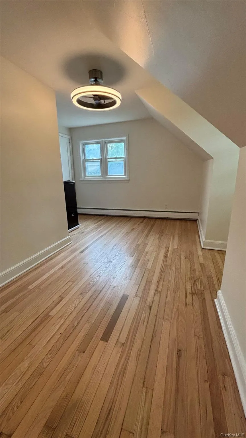 Additional living space with light wood-type flooring, baseboard heating, and lofted ceiling Additional living space with light wood-type flooring, baseboard heating, and lofted ceiling