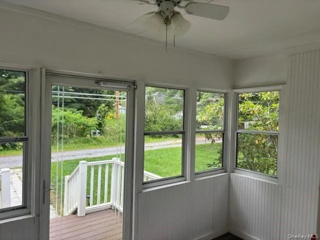 Enclosed porch featuring beadboard wall paneling, a ceiling fan, and multiple windows Enclosed porch featuring beadboard wall paneling, a ceiling fan, and multiple windows